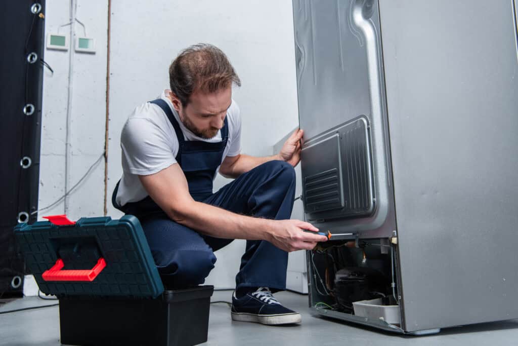 Appliance repair service working on a refrigerator