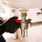plumber using a wrench repairing a sink