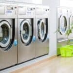 Public laundry with modern, silver washing machines in a row